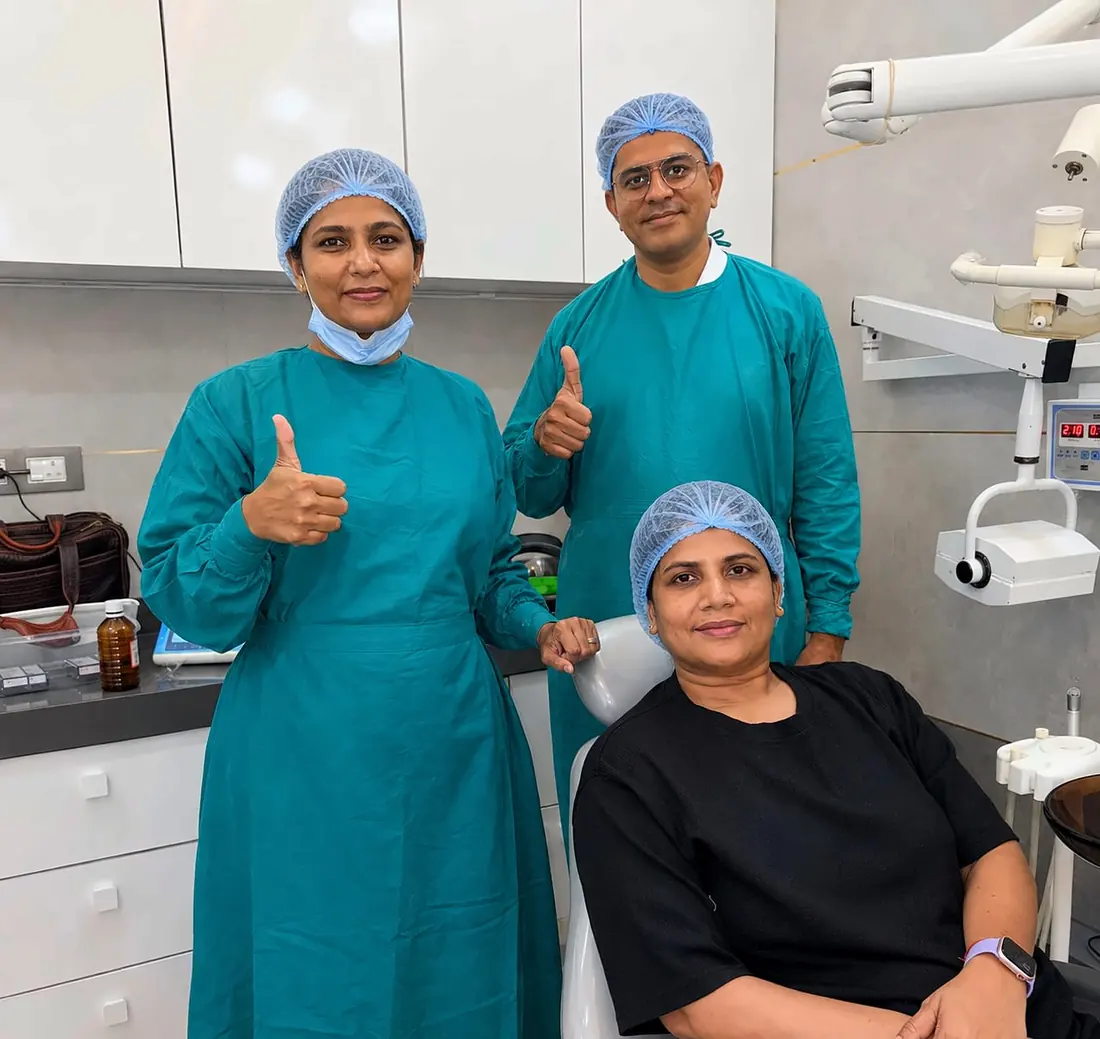 The clinic team in surgical scrubs with a patient, giving a thumbs up