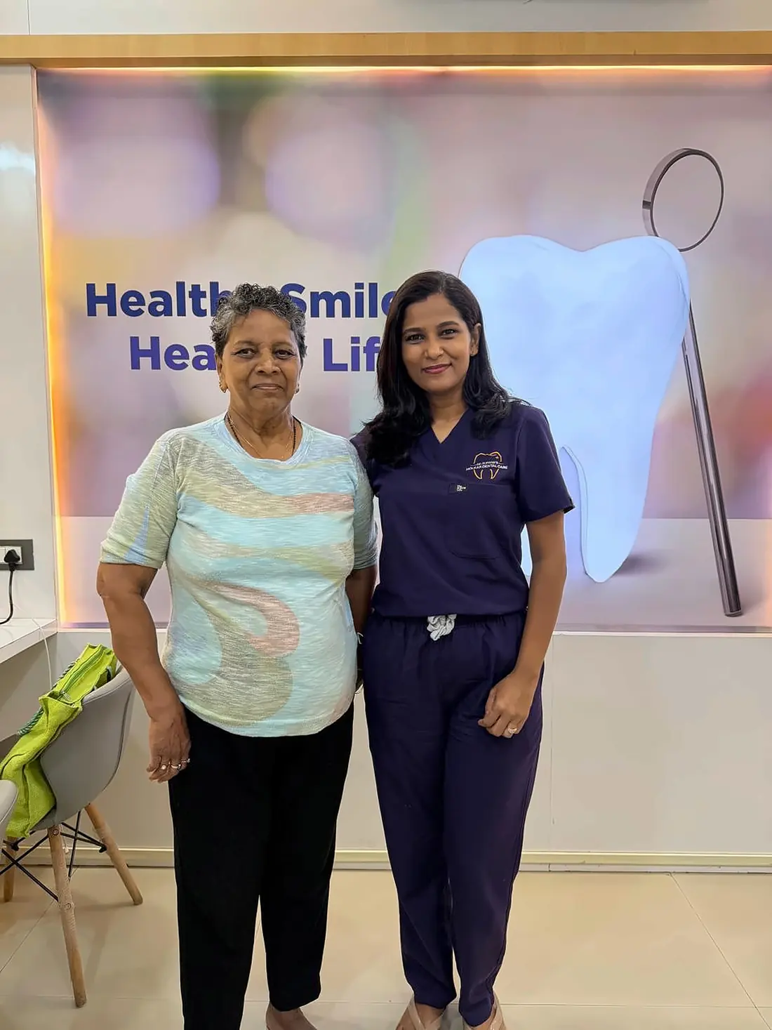 Dr. Supriya Holkar with a senior patient in front of the Healthy Smile wall